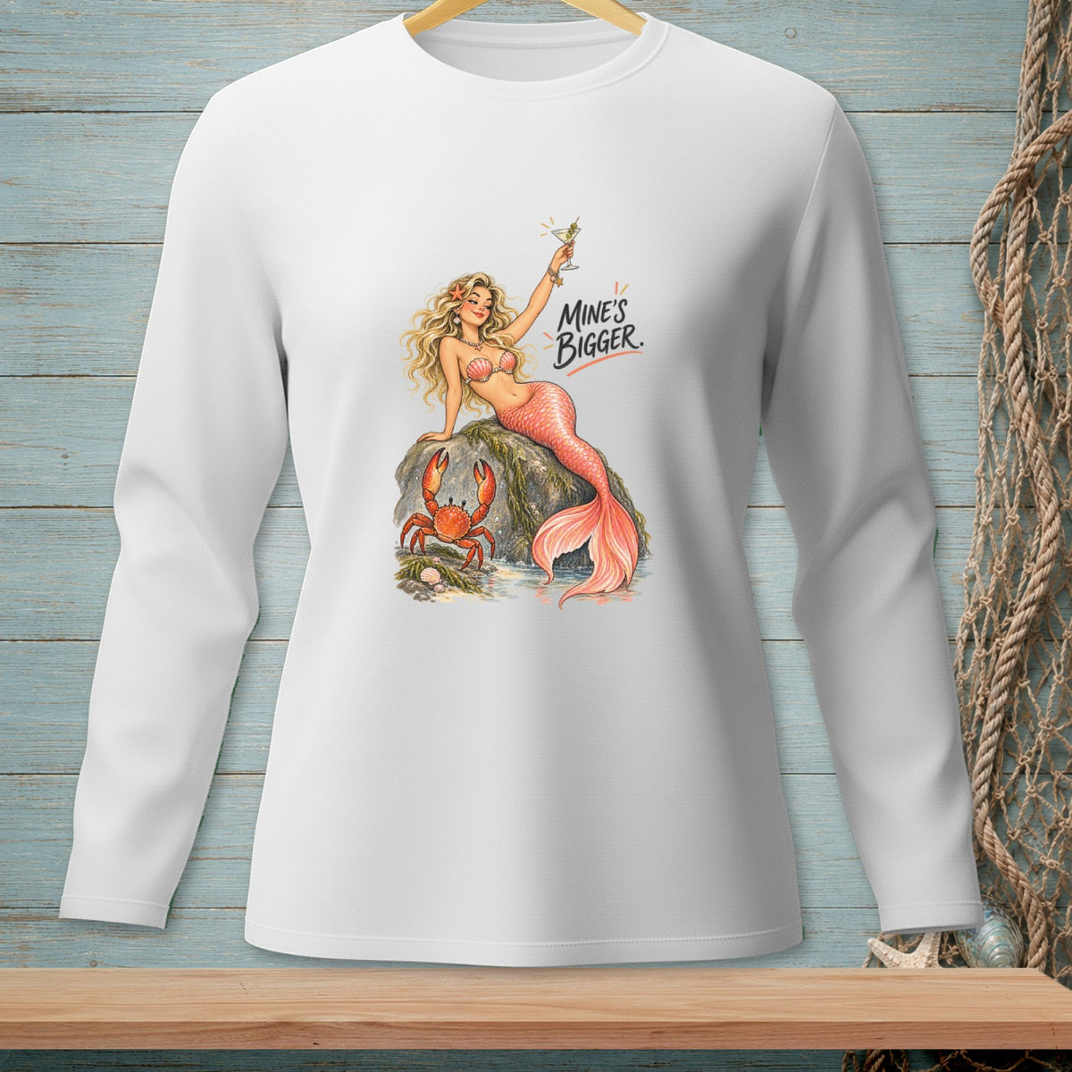 White long-sleeve shirt with a graphic of a mermaid, crab, and text "Mine's Bigger."