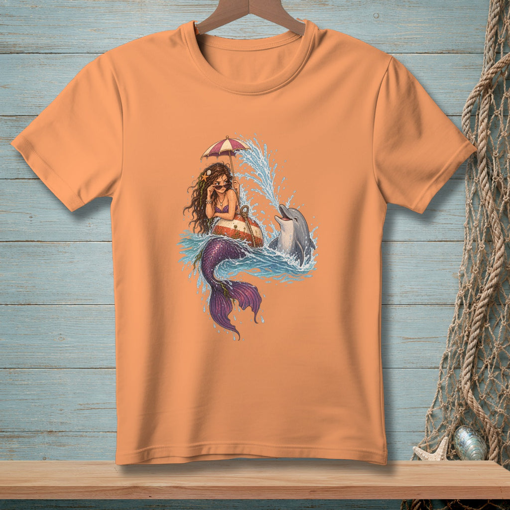 Mermaid and dolphin with umbrella in ocean waves graphic on an orange t-shirt.