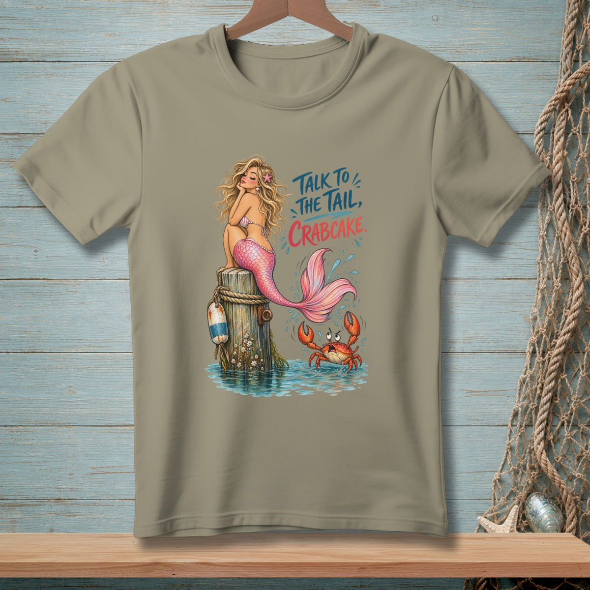 Mermaid with pink tail sits on post with crab, text "Talk to the tail, Crabcake."
