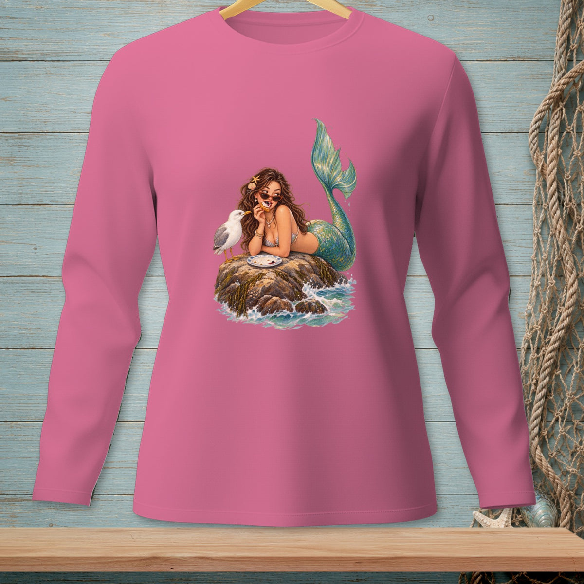 Mermaid with a donut and seagull on rocks with waves.