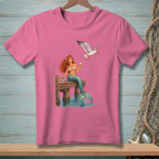 Pink t-shirt with graphic of a mermaid and a seagull on a dock.