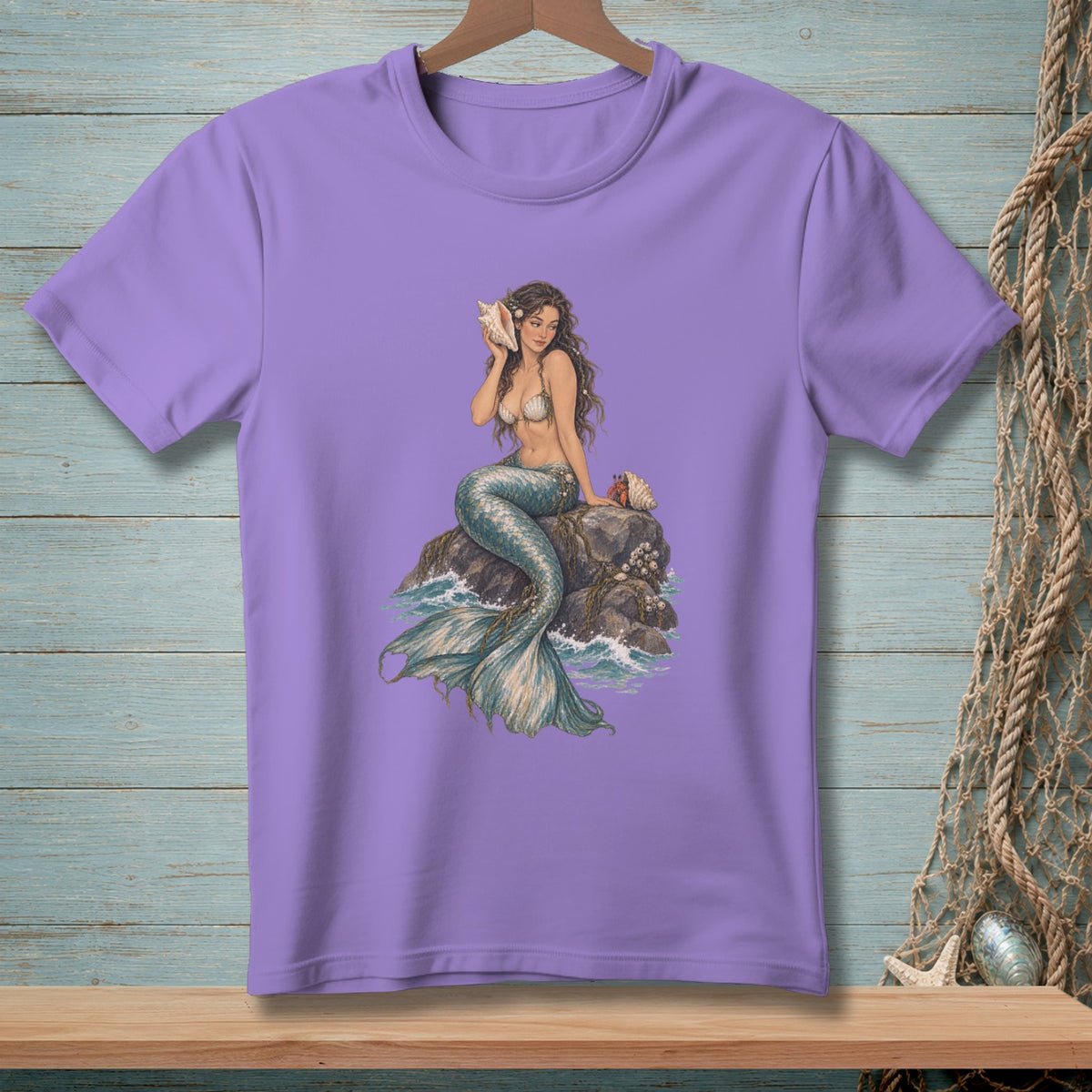 Purple t-shirt with illustration of a mermaid holding a conch shell on rocks.