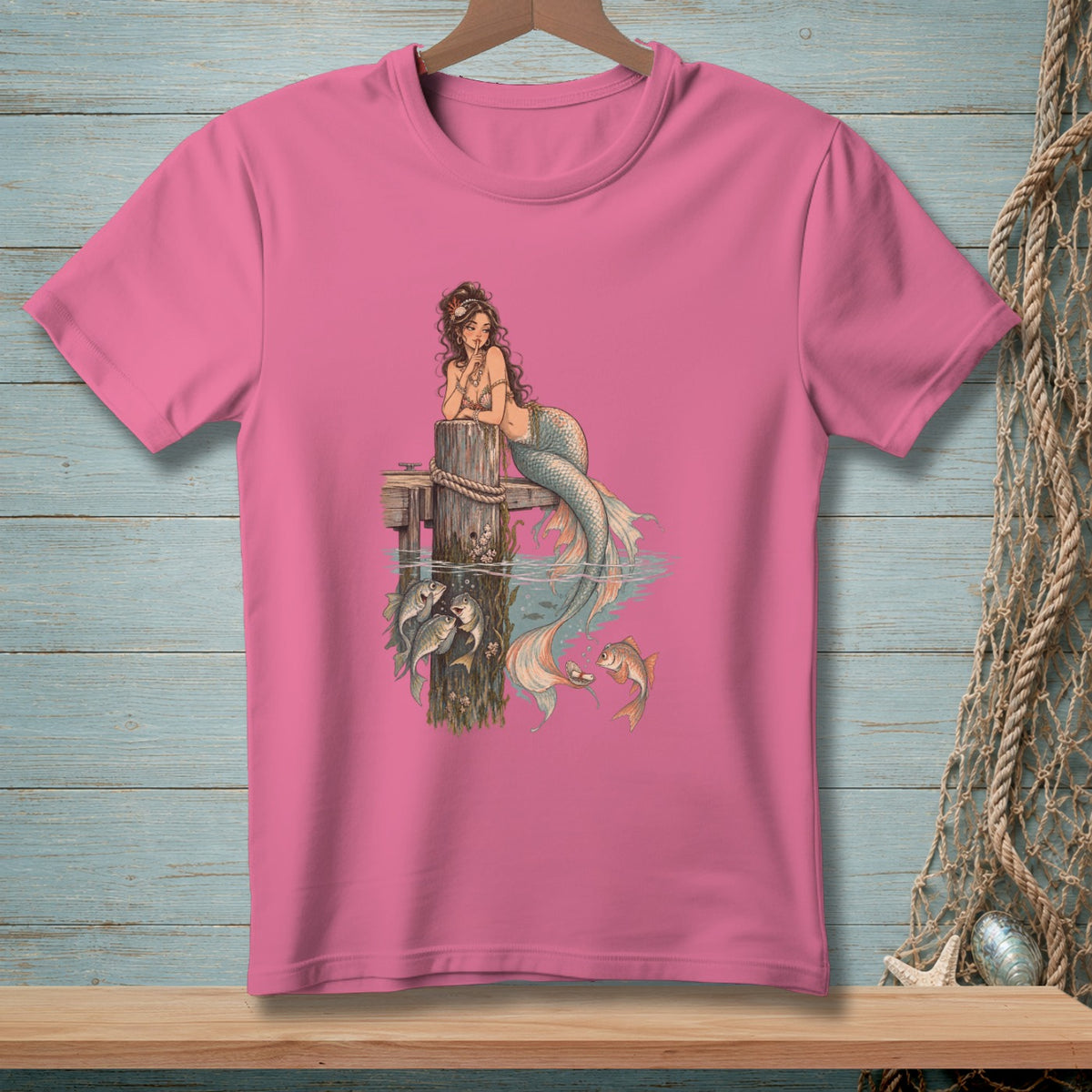 Pink t-shirt featuring a whimsical mermaid with fish around a wooden post.