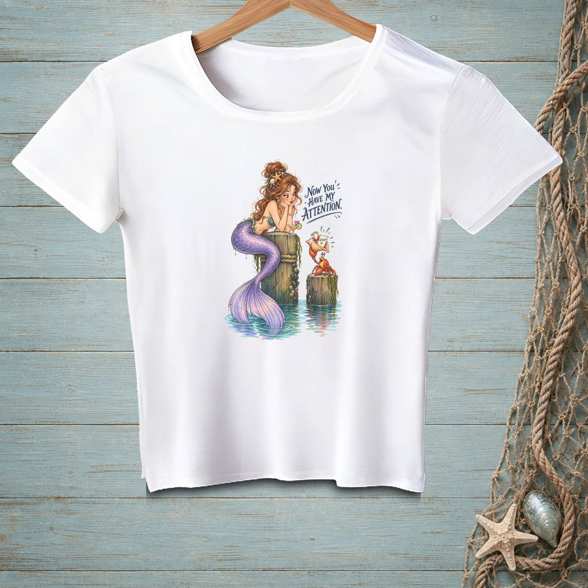 White t-shirt with mermaid and crab illustration, reading "Now You've Have My Attention".
