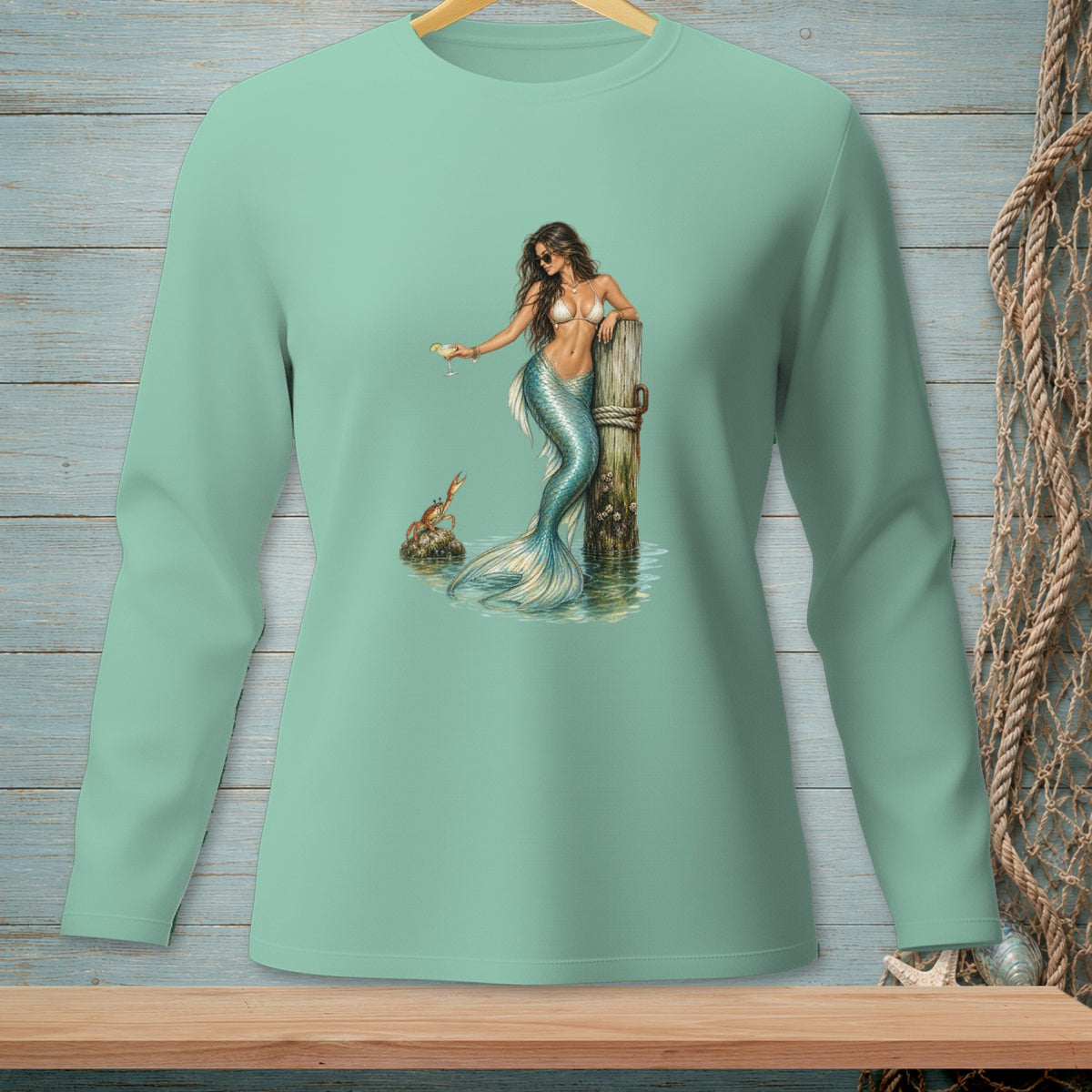 Mint green long-sleeve shirt with a detailed graphic of a mermaid holding a drink.