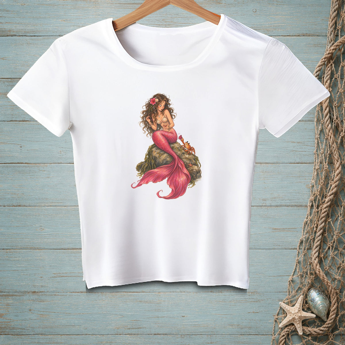 White t-shirt with a mermaid illustration sitting on a rock with two crabs.