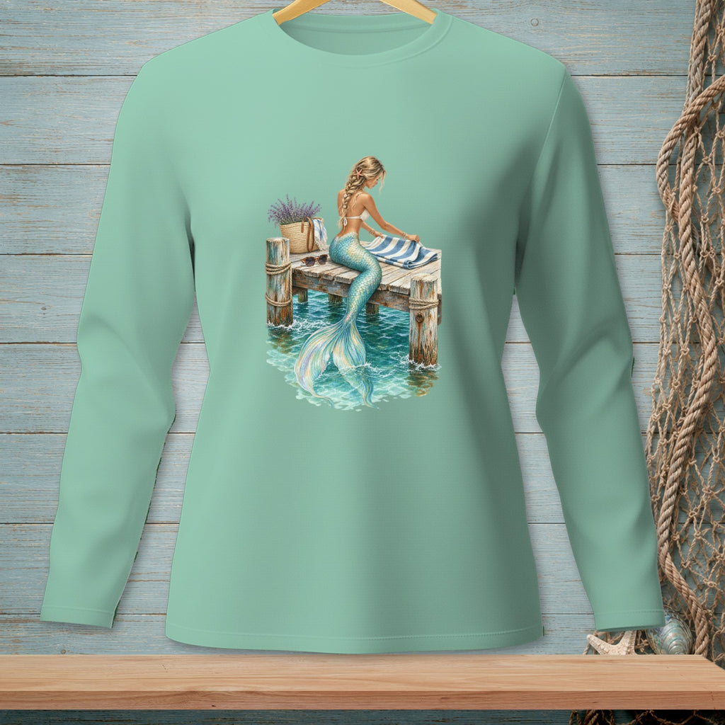 Mermaid sitting on a dock with a striped towel and a basket of lavender.