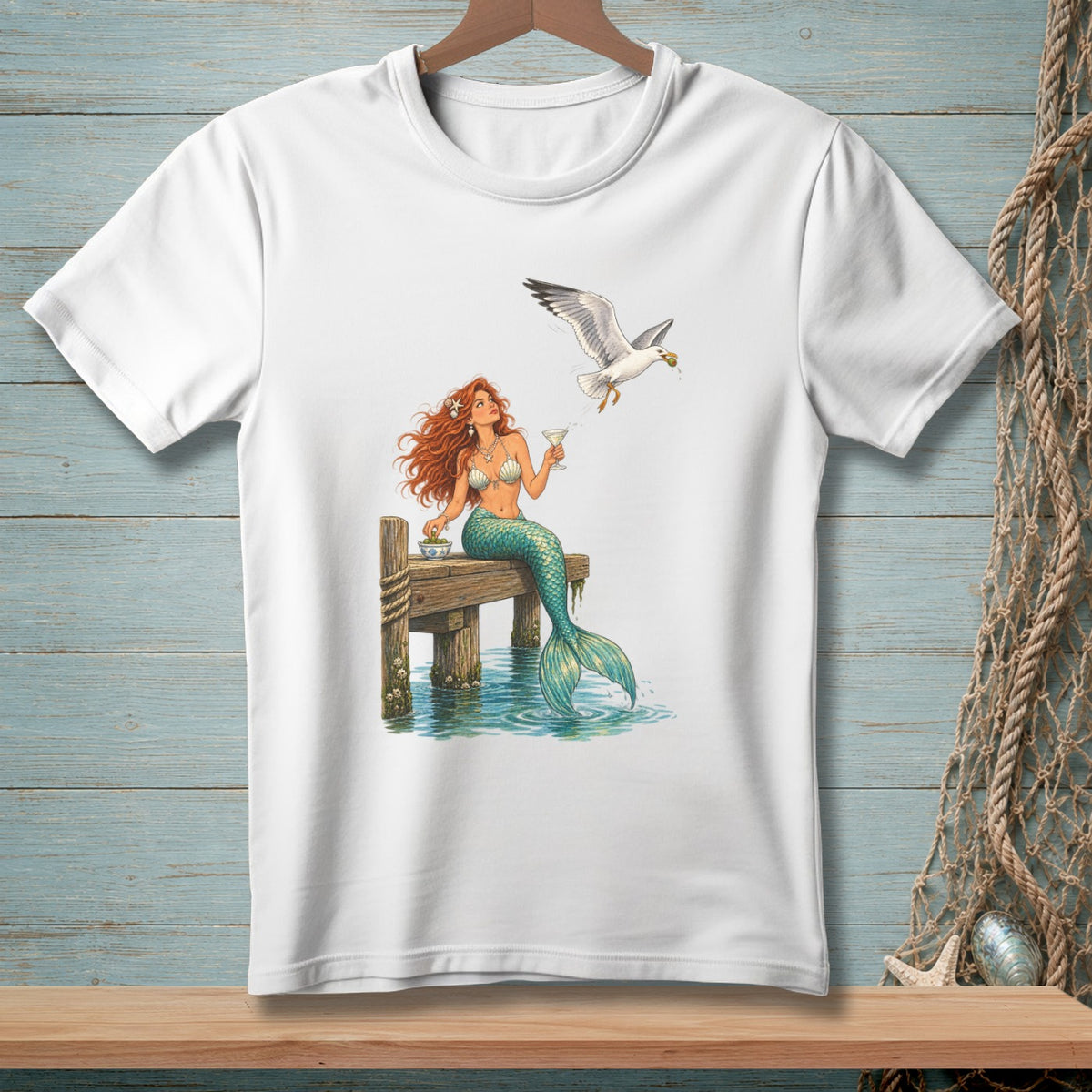 Mermaid with red hair sits on a dock with a drink while a seagull flies overhead.