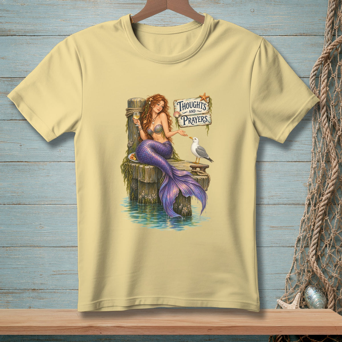 Mermaid on a dock with a glass of wine and a seagull, "Thoughts and Prayers" sign.
