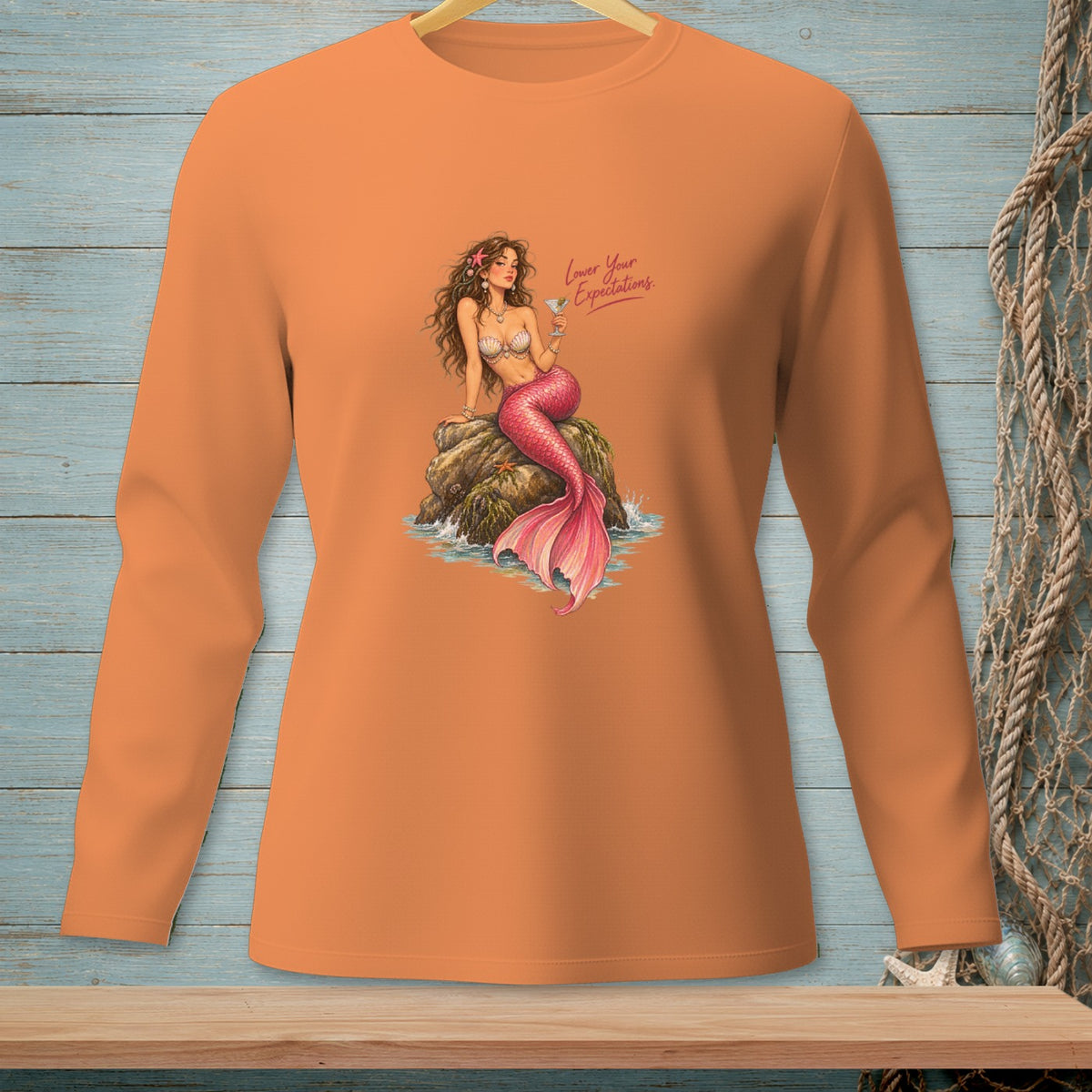 Orange long-sleeve shirt with a mermaid illustration and the text "Lower Your Expectations."