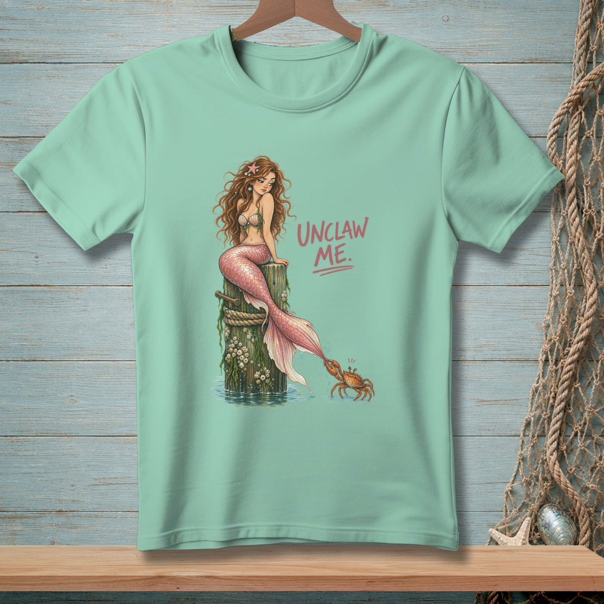 Mint t-shirt with mermaid on post and crab with text "UNCLAW ME."