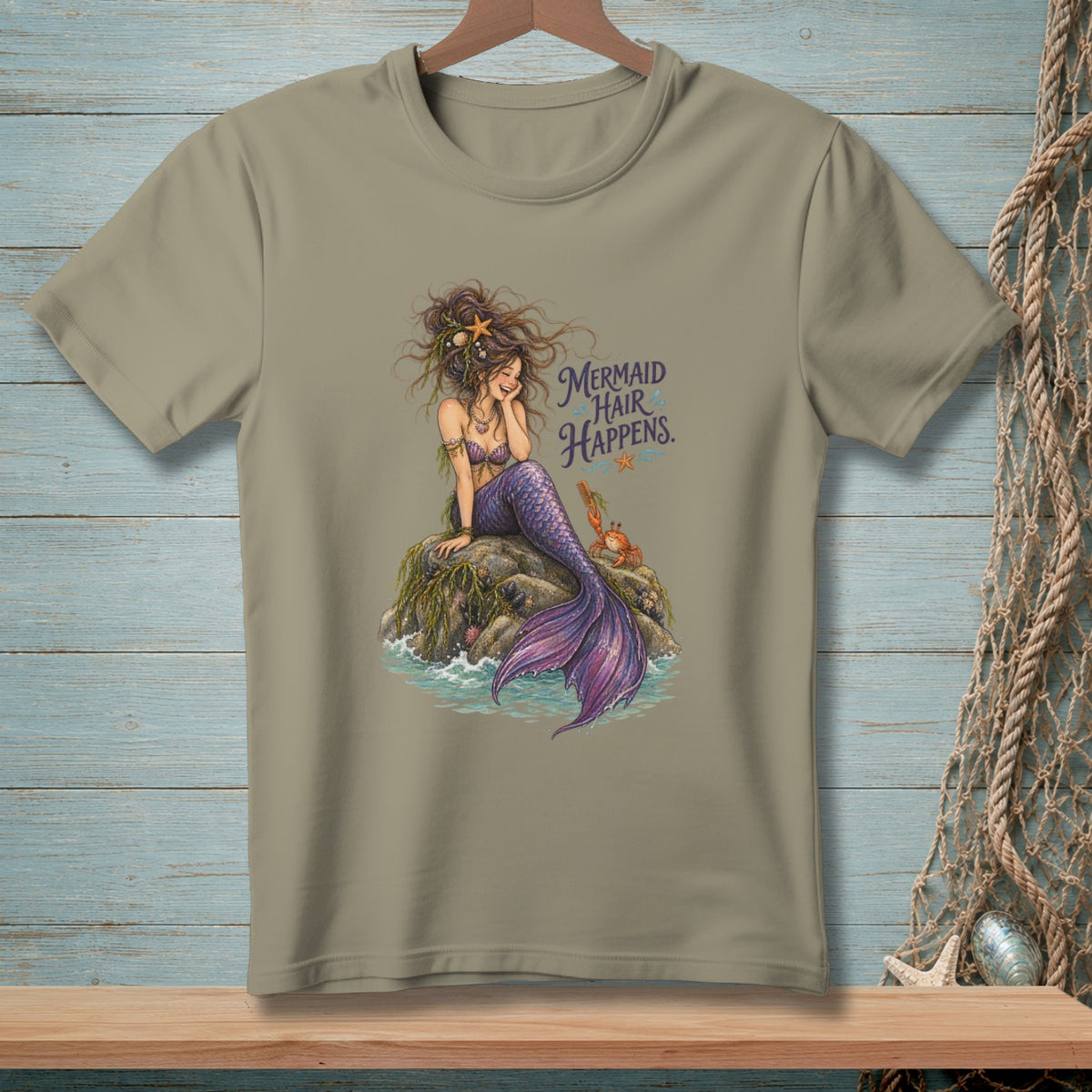 T-shirt with a mermaid sitting on a rock and the text "Mermaid Hair Happens."