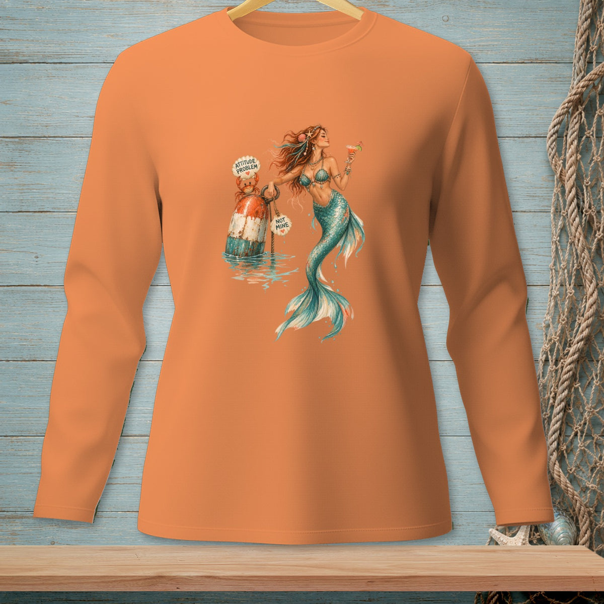 Orange long-sleeve shirt with a graphic of a mermaid holding a drink and a buoy labeled "ATTITUDE PROBLEM".