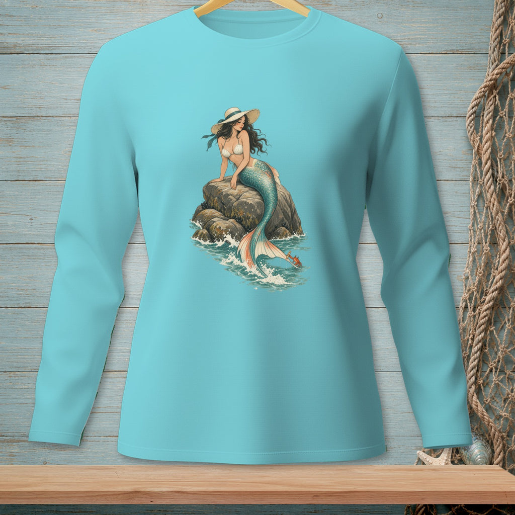 Long sleeve teal shirt with a mermaid illustration on a rock in the ocean.