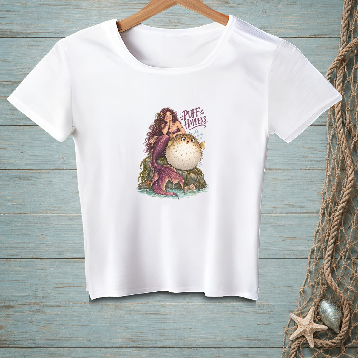 White t-shirt with mermaid and pufferfish graphic and text "PUFF HAPPENS."