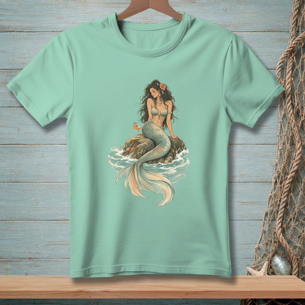 Mint green t-shirt with a mermaid sitting on a rock in the ocean.