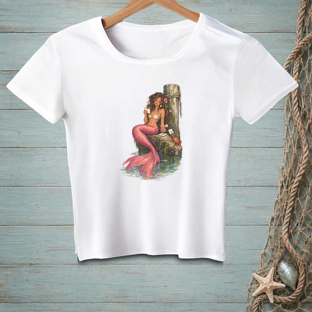 White t-shirt with a mermaid holding a letter on a weathered post.