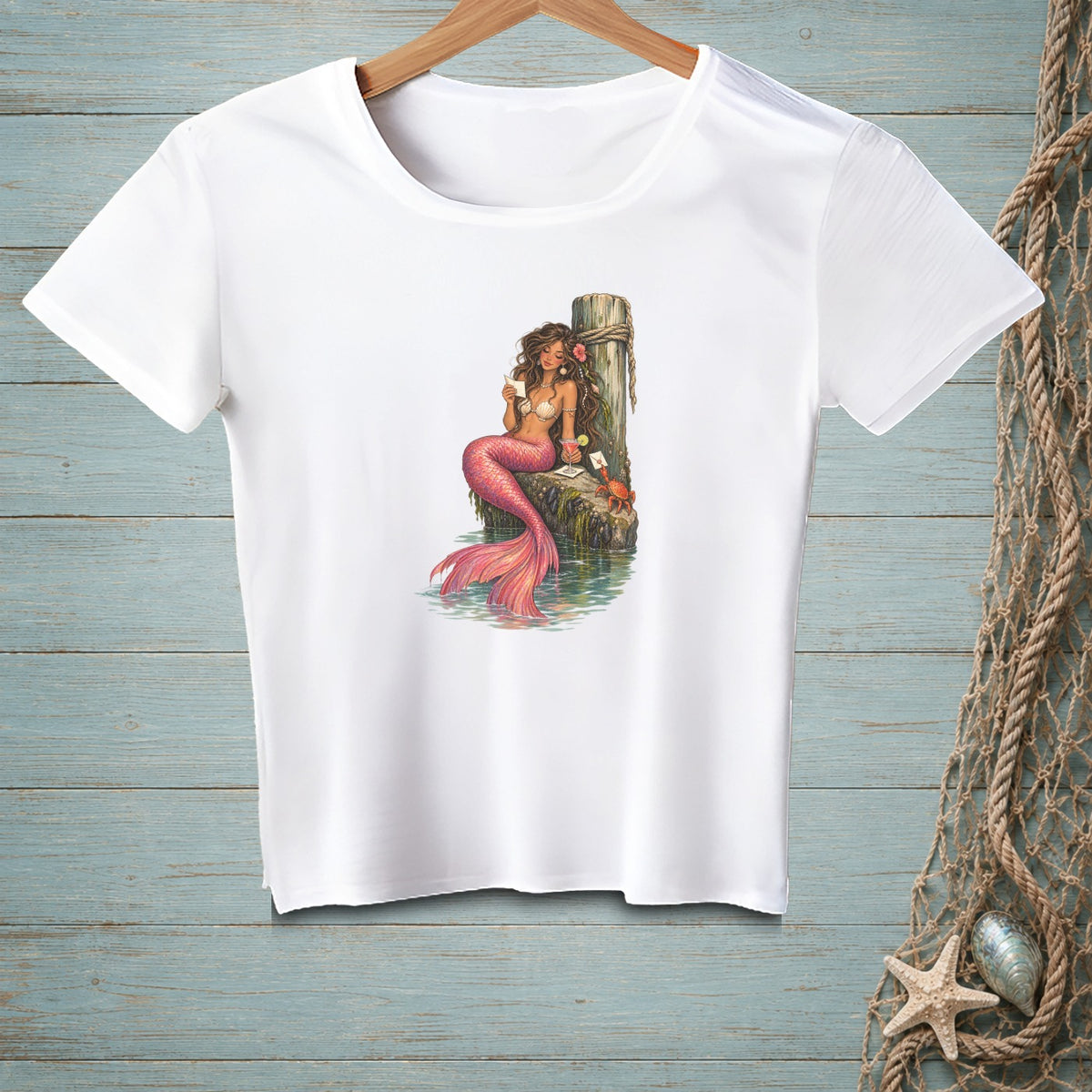 White t-shirt with a mermaid holding a letter on a weathered post.