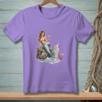 Purple t-shirt featuring a mermaid sitting on a rock with a cocktail and a crab holding a "Be Nice" sign.