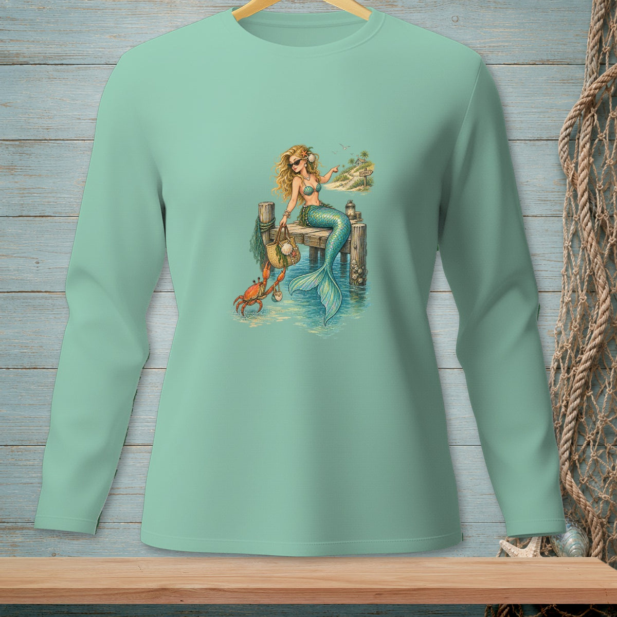 Mermaid with crab sits on a dock by the ocean.