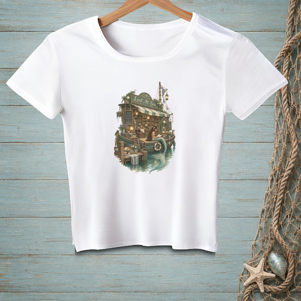 White t-shirt with a mermaid reading by a floating bookstore labeled "Lost At Sea".