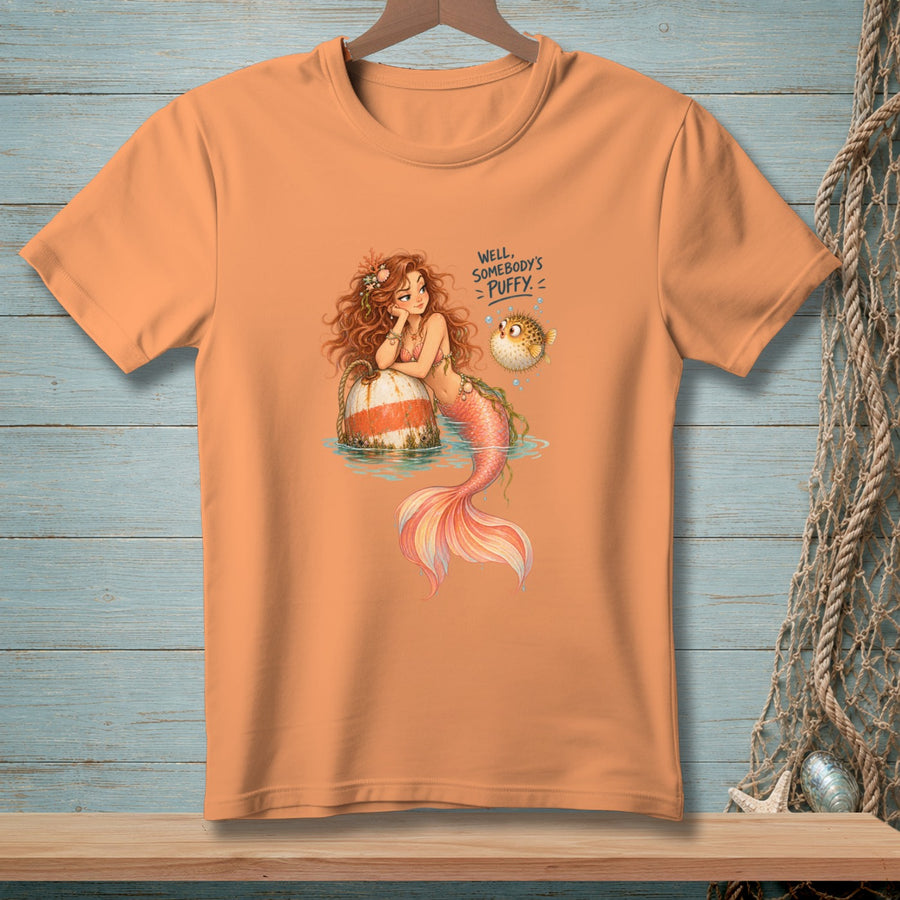 Orange t-shirt graphic: mermaid with text "Well, somebody's puffy" next to a pufferfish.