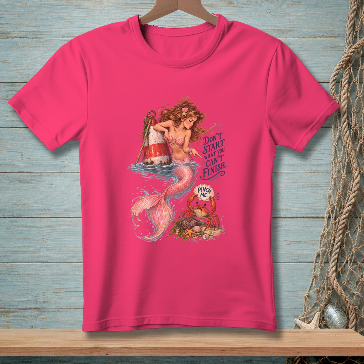 Pink t-shirt with a mermaid, buoy, and crab graphic. Text says "Don't start what you can't finish. Pinch me."