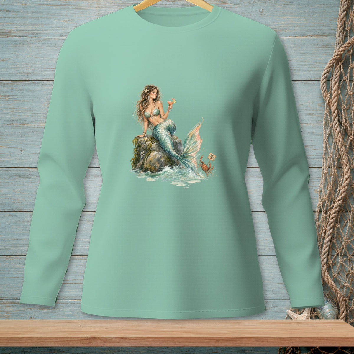 Green long-sleeved shirt with a graphic of a mermaid holding a drink and a crab.
