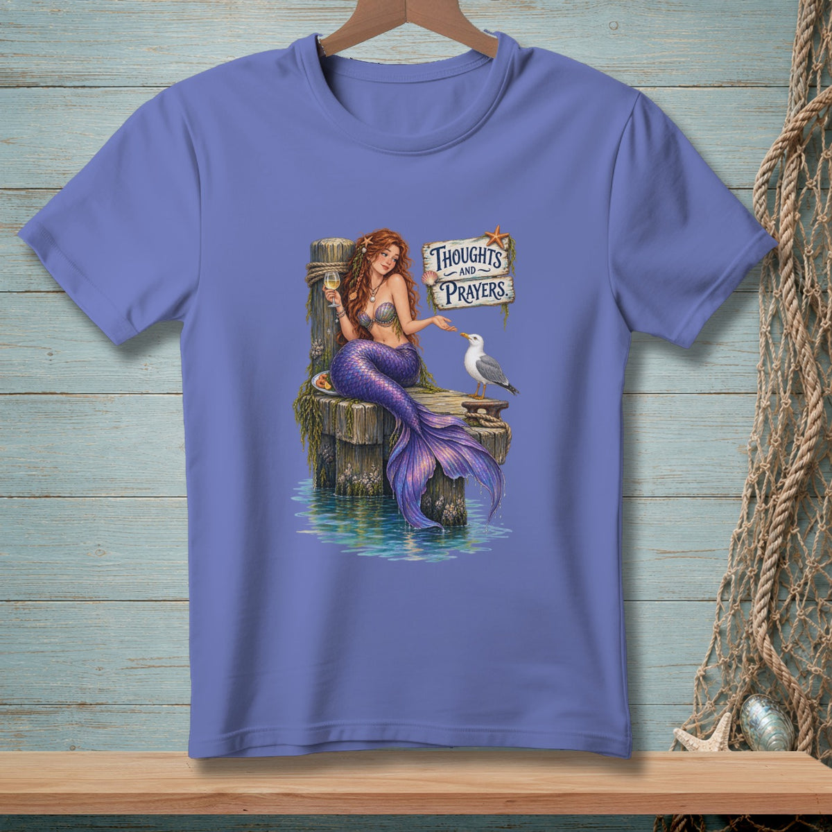 Mermaid on dock with seagull and glass, "Thoughts and Prayers" sign.