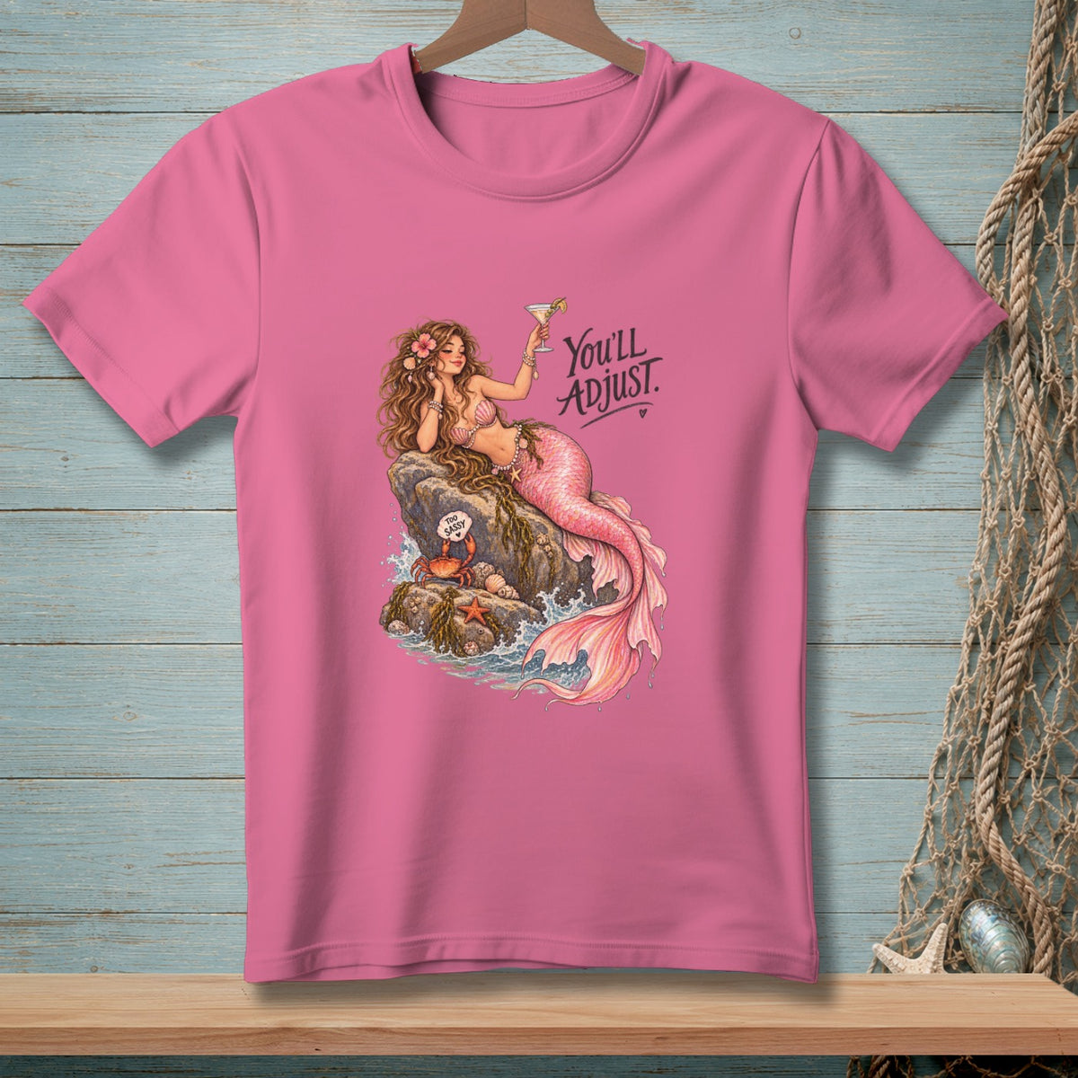 Pink t-shirt with a mermaid holding a cocktail, text reads "You'll Adjust."