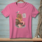 Pink t-shirt with a mermaid sitting on a pier with a seagull and a sign.