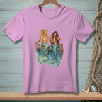 Pink t-shirt with illustration of two mermaids sitting on a dock drinking wine.