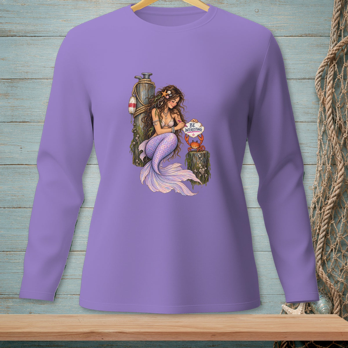 Purple long-sleeve shirt with a mermaid holding a heart-shaped sign that says "BE INTERESTING".