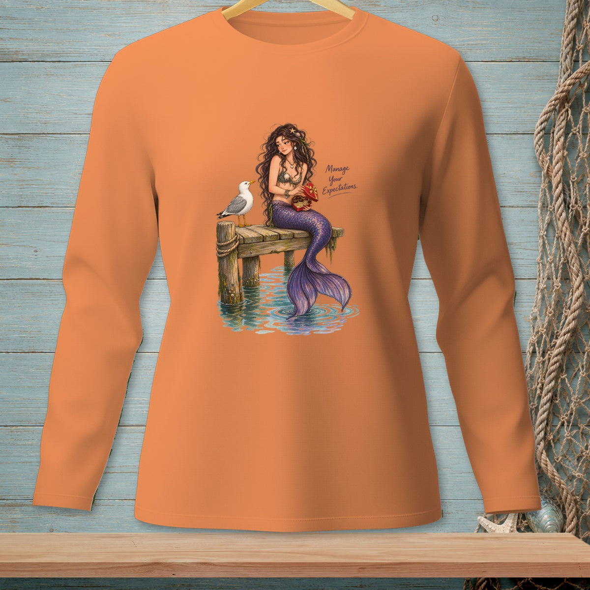 Orange long sleeve shirt with mermaid illustration and text "Manage Your Expectations".
