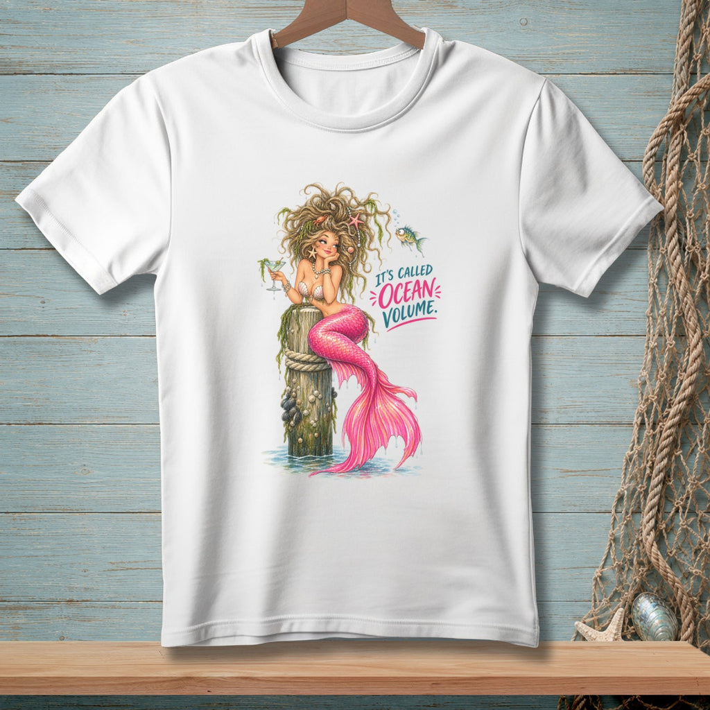White t-shirt with a mermaid sitting on a wooden post, text reads "It's called Ocean Volume."