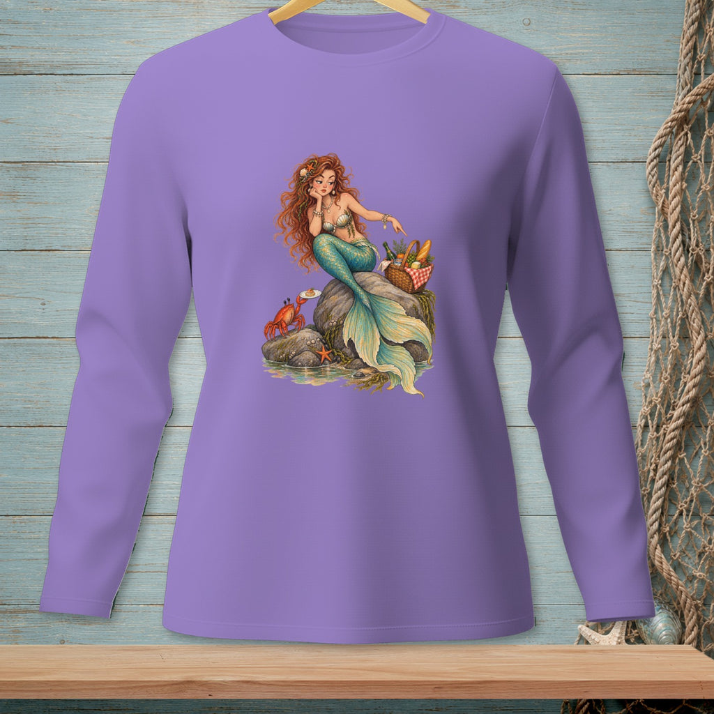 Illustration of a mermaid on a rock with a crab and picnic basket on a purple long-sleeved shirt.