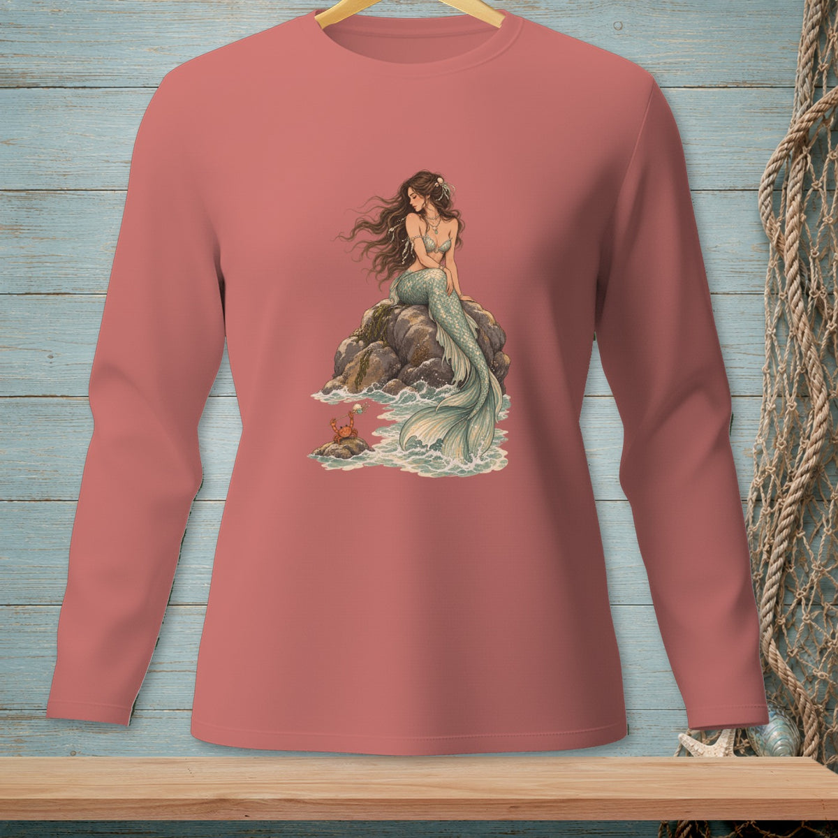Mermaid with a crab on a rock by the sea, printed on a pink long-sleeved shirt.