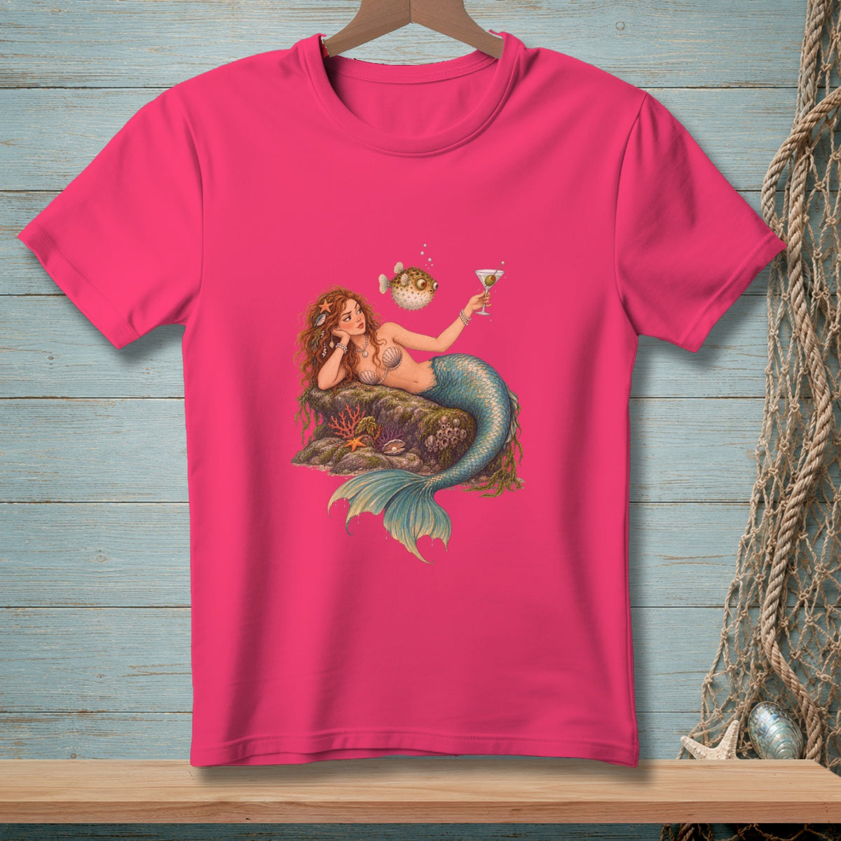 Pink t-shirt with a mermaid holding a cocktail and a pufferfish.