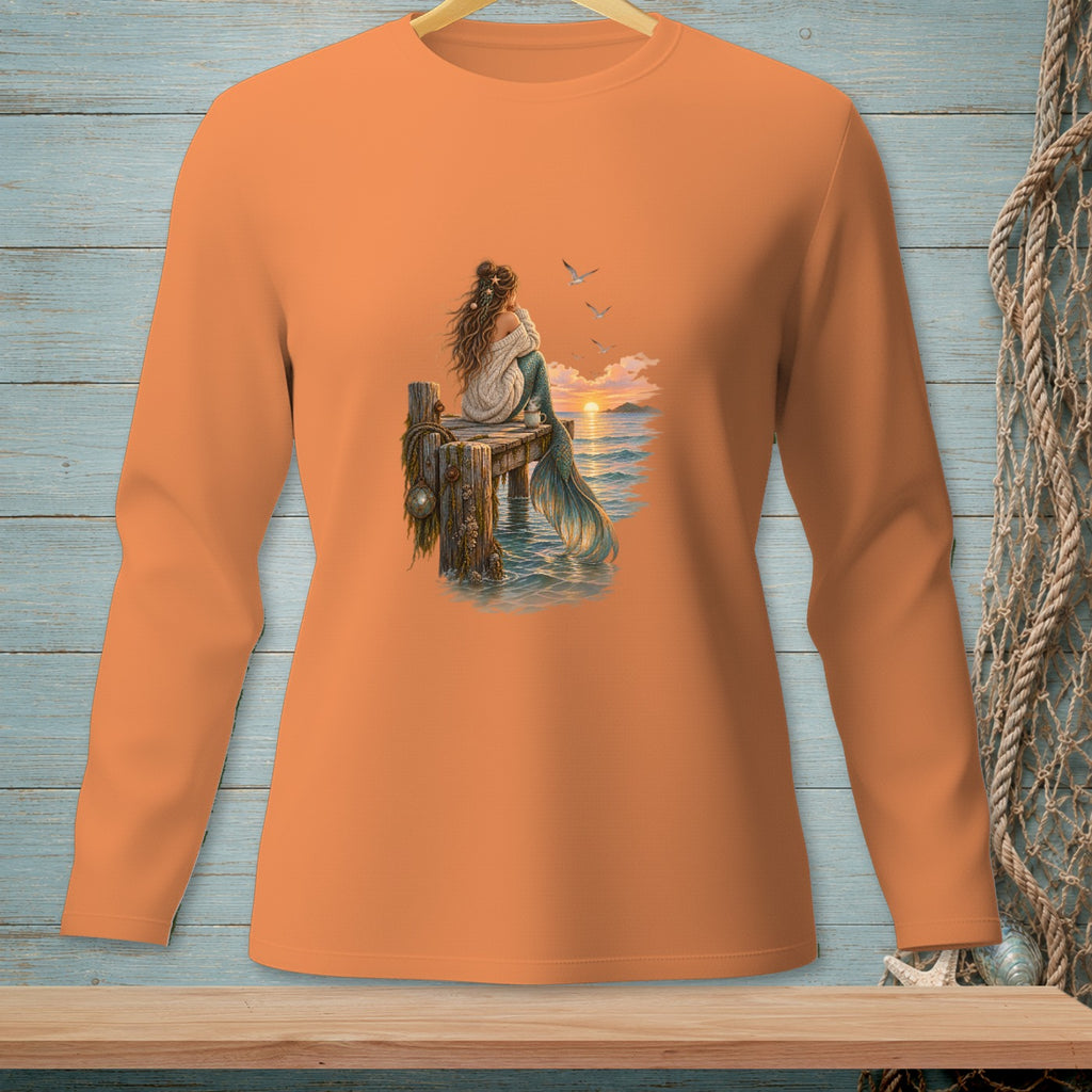 Orange long-sleeve shirt with a mermaid sitting on a dock watching a sunset.