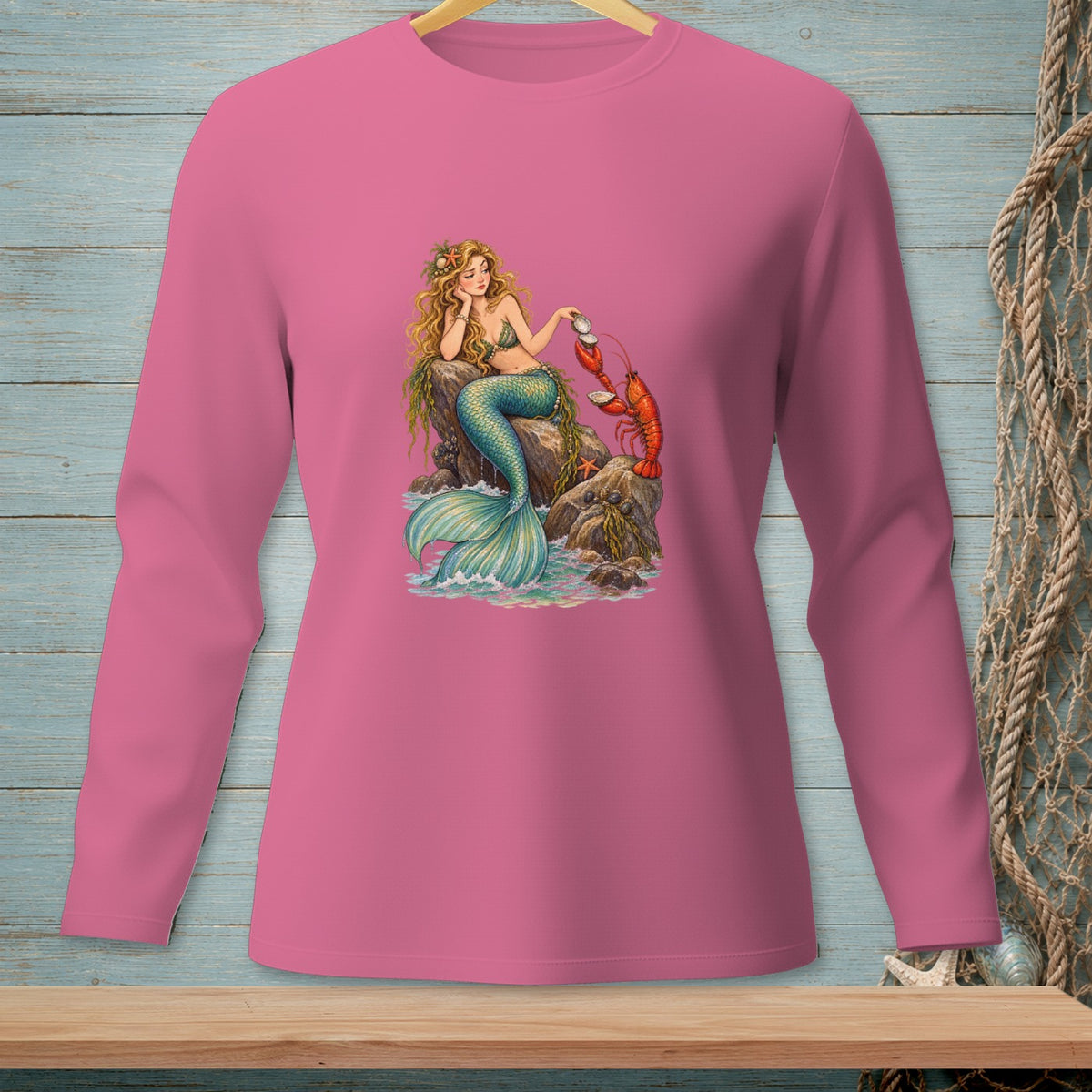 Pink long-sleeve shirt with a mermaid interacting with a lobster on rocks.