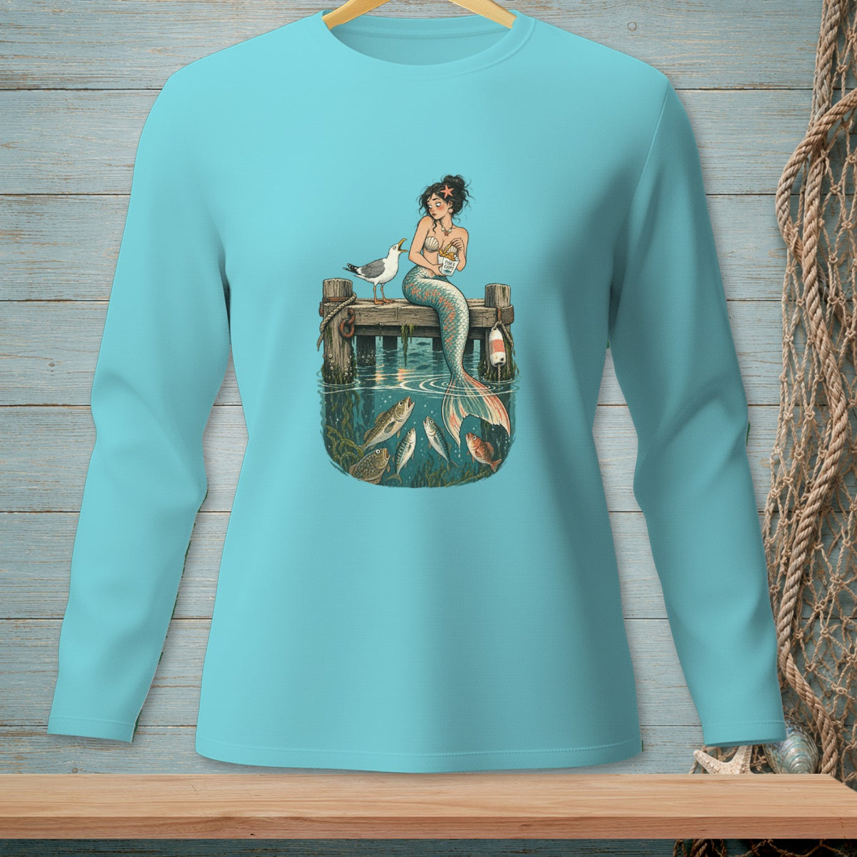 Mermaid sitting on pier with fish and seagull, blue long-sleeve shirt.