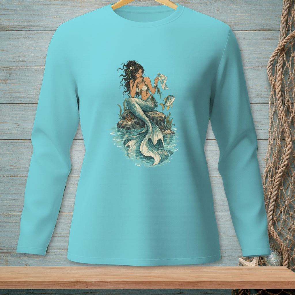 Long sleeve t-shirt with a blue mermaid reading on a rock next to a fish.