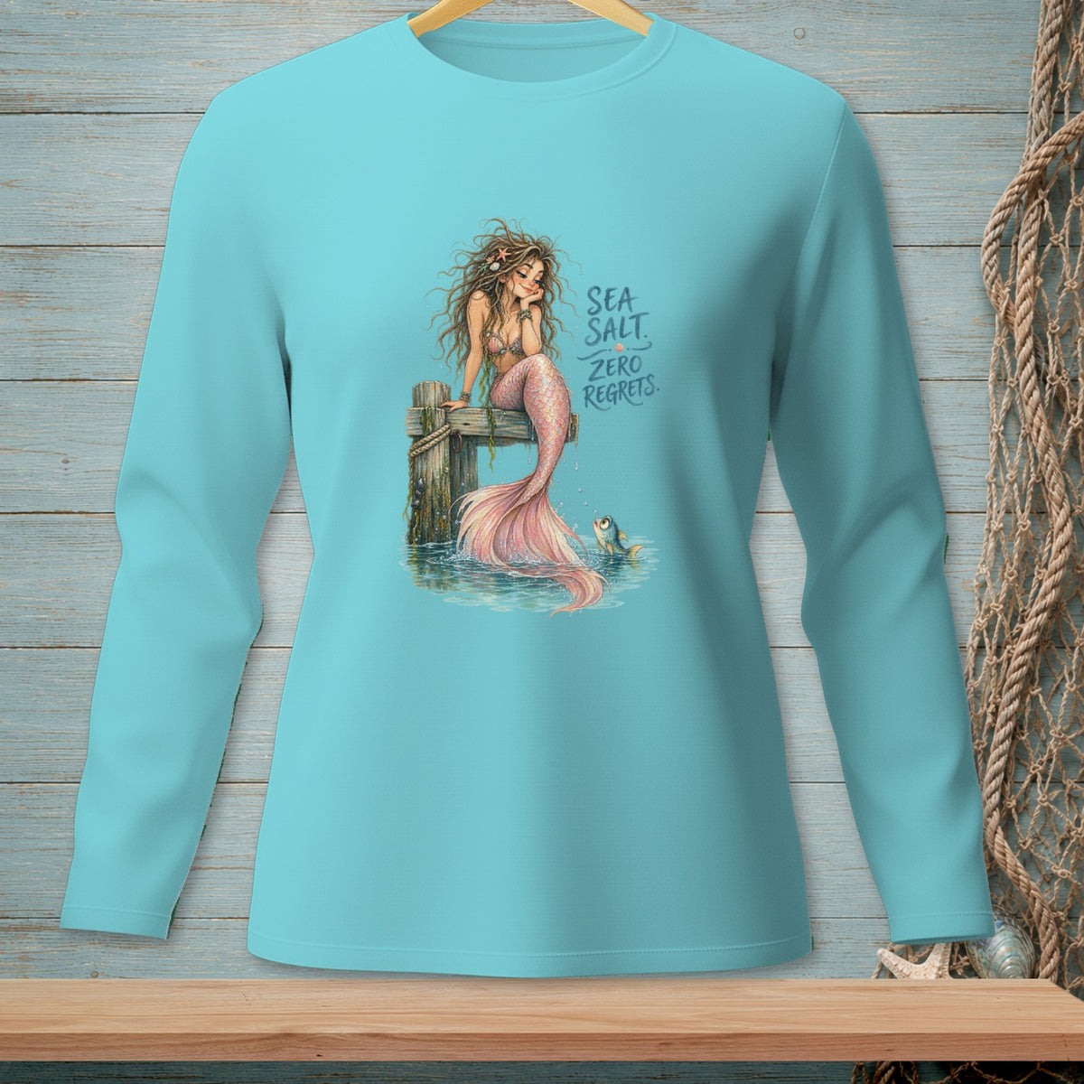 Mermaid with pink tail and text "SEA SALT. ZERO REGRETS." on blue shirt.