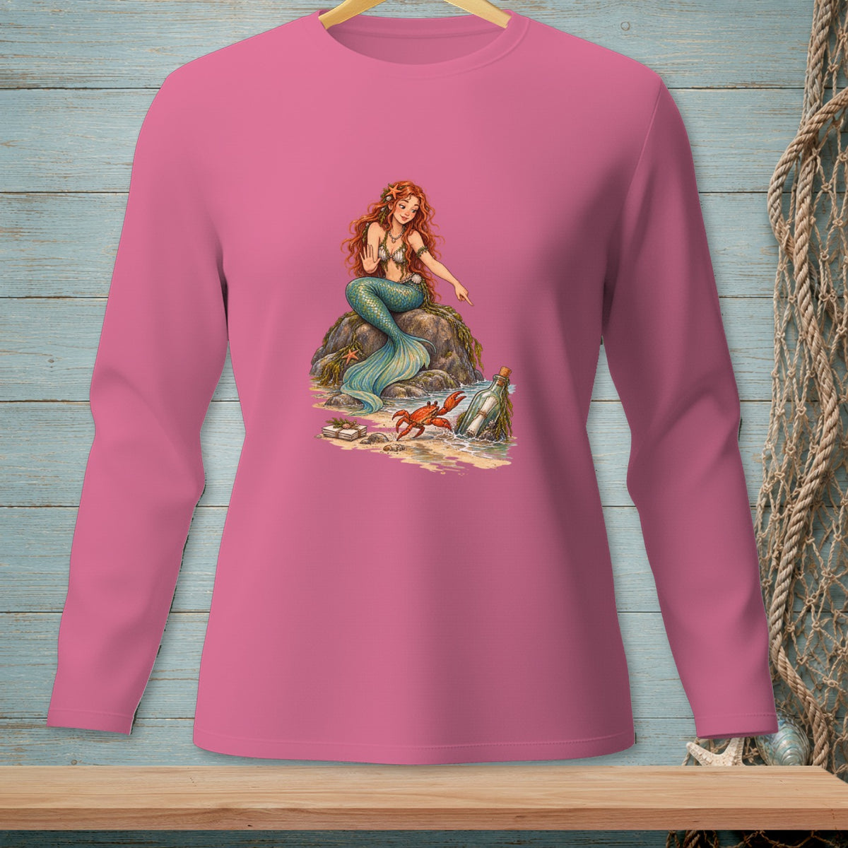 Pink long-sleeve shirt featuring a mermaid, crab, and message in a bottle illustration.
