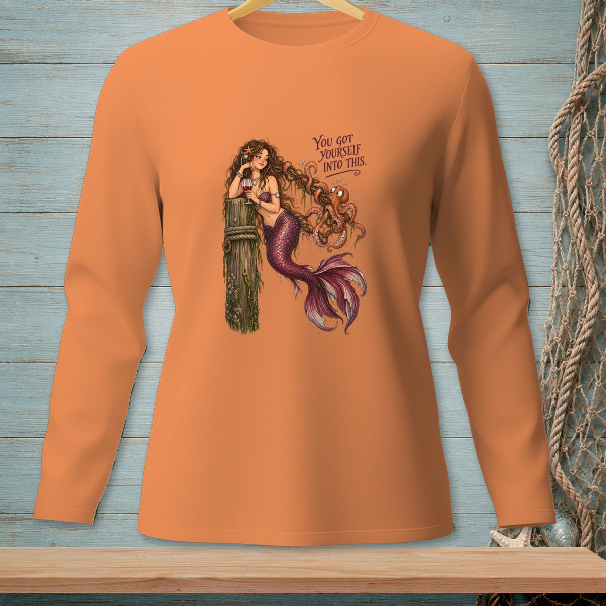 Orange long-sleeve shirt with a mermaid and octopus graphic and text.