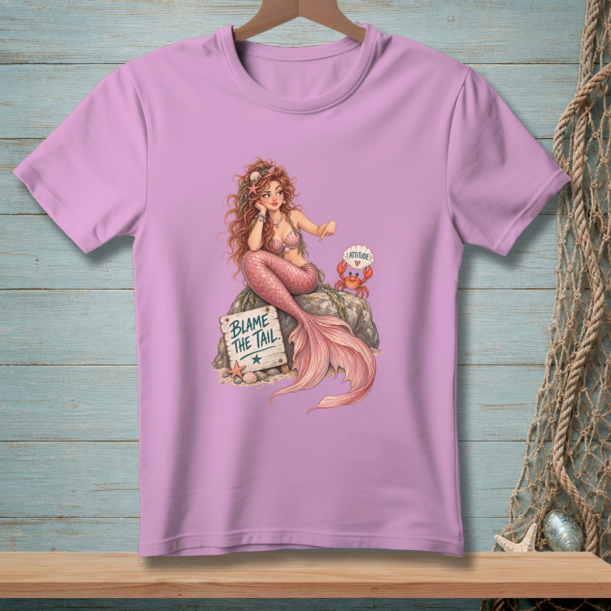 Pink t-shirt with mermaid, crab, and sign reading "BLAME THE TAIL".