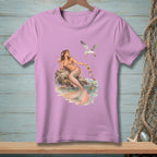 Lilac t-shirt with a mermaid and seagull graphic at the beach.