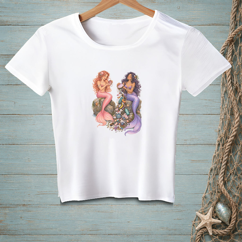 White t-shirt with two mermaids sitting on rocks surrounded by treasures.