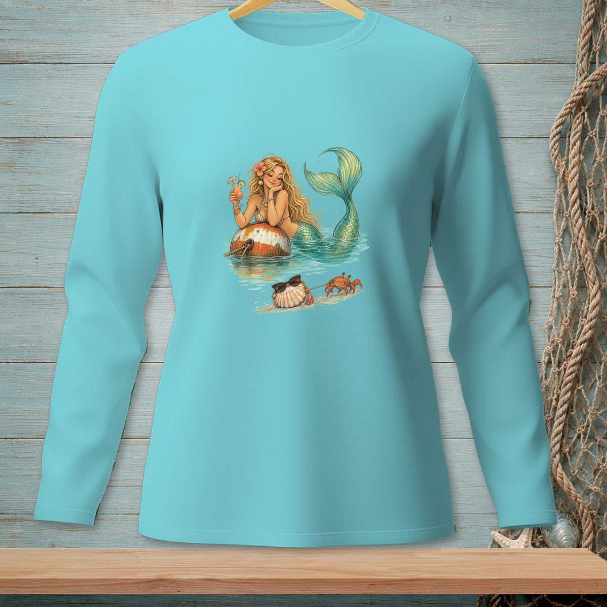 Turquoise long-sleeve shirt featuring a smiling mermaid with a drink and a crab.