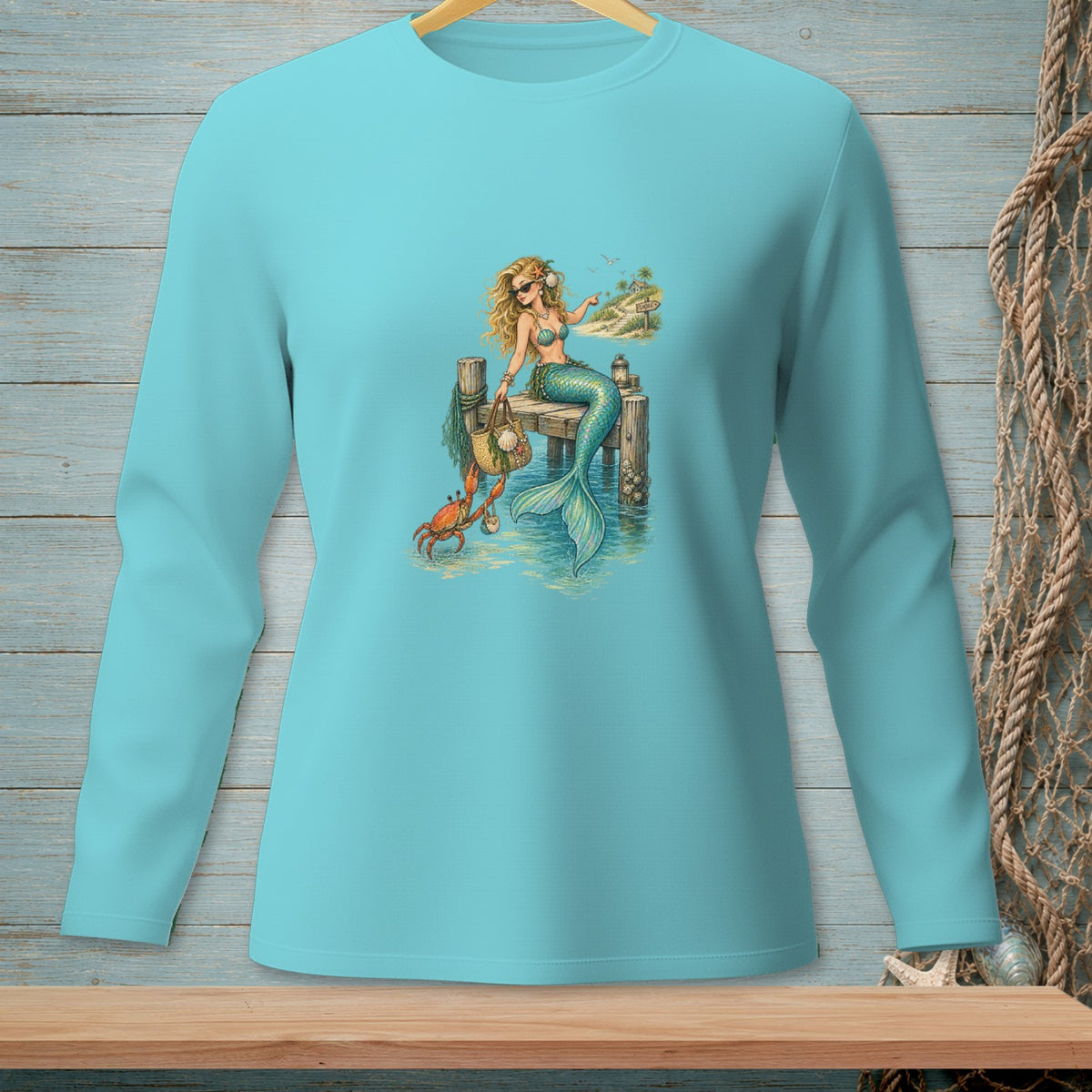 Mermaid on dock with crab, beach sign, and handbag on light blue long-sleeve shirt.